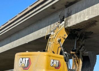 A Semi Hit a Bridge in Kansas so Hard the Excavator It Was Hauling Punched a Hole in the Road Above It